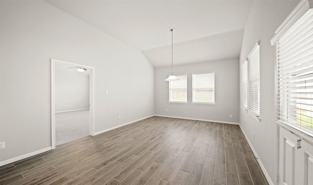 unfurnished room featuring baseboards, lofted ceiling, and wood finished floors