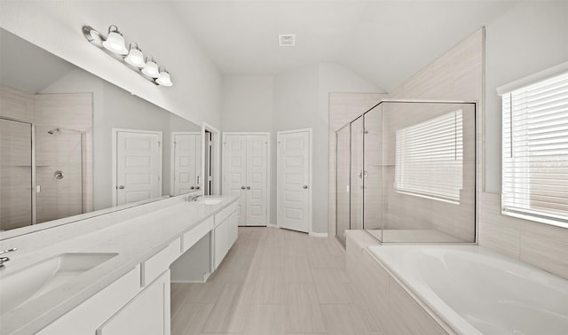 full bathroom featuring double vanity, a sink, a shower stall, and vaulted ceiling