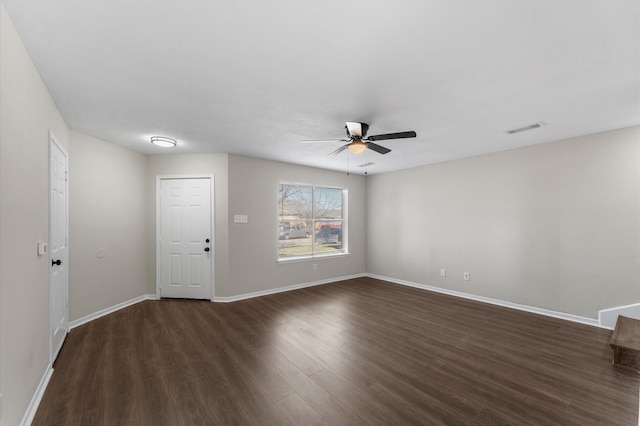 unfurnished room featuring baseboards, visible vents, dark wood-style flooring, and ceiling fan