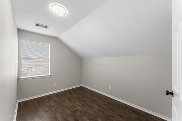 additional living space featuring dark wood finished floors, lofted ceiling, baseboards, and visible vents