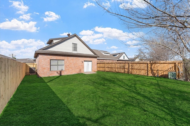 back of house with cooling unit, a lawn, a fenced backyard, and brick siding