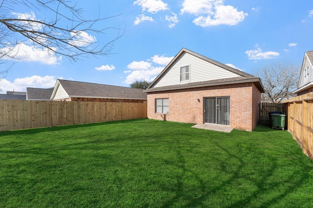 back of property featuring a lawn, brick siding, and a fenced backyard