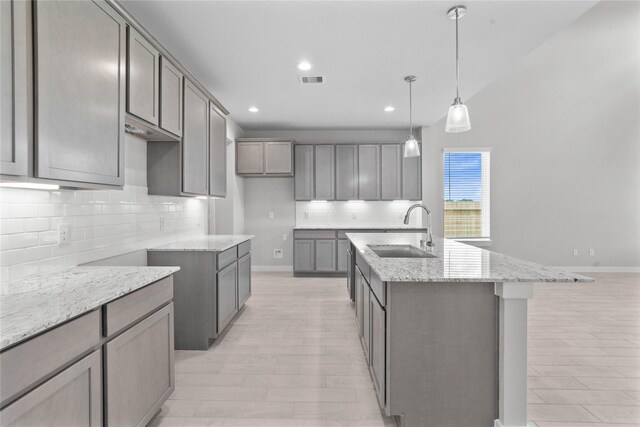 357 Spruce Oak Ln, Waller, TX 77484 - kitchen featuring a sink, light stone countertops, decorative backsplash, an island with sink, and recessed lighting
