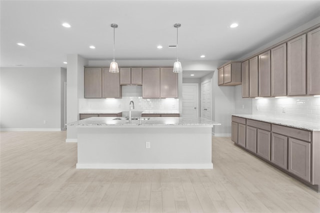 357 Spruce Oak Ln, Waller, TX 77484 - kitchen featuring a center island with sink, tasteful backsplash, baseboards, a sink, and recessed lighting