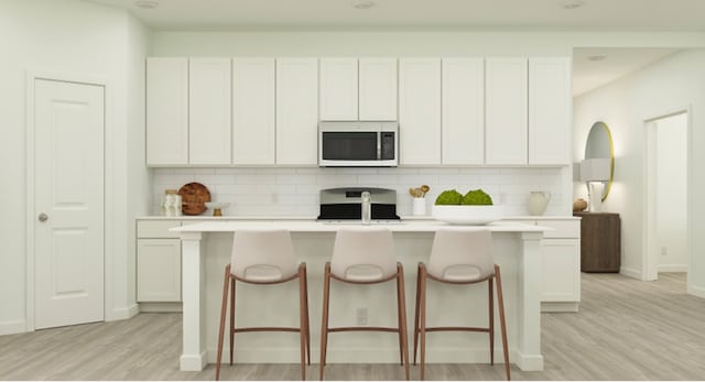 kitchen featuring stove, white microwave, light wood-type flooring, and backsplash