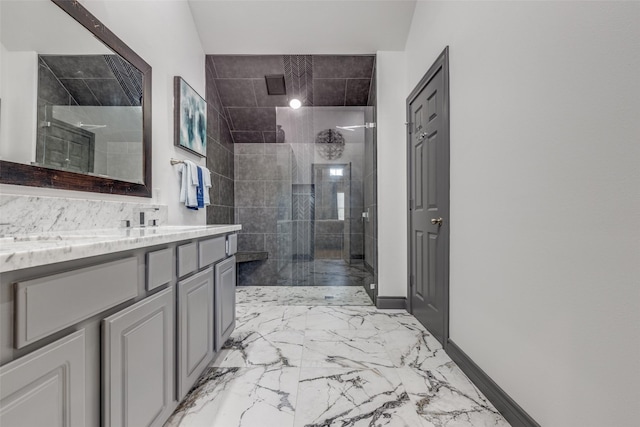 full bathroom featuring marble finish floor, a walk in shower, vanity, and baseboards