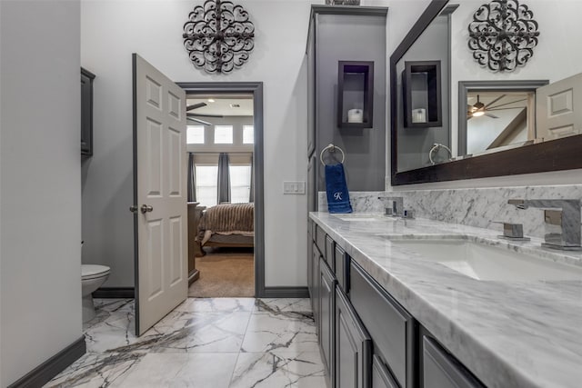 ensuite bathroom with ceiling fan, a sink, toilet, marble finish floor, and connected bathroom