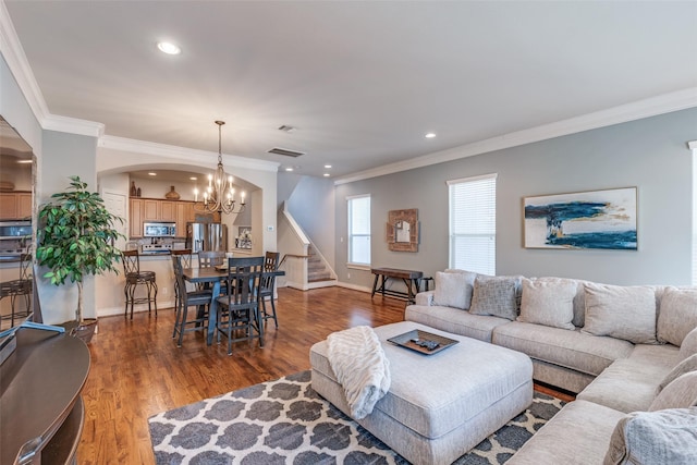 living room featuring visible vents, a chandelier, stairway, wood finished floors, and arched walkways