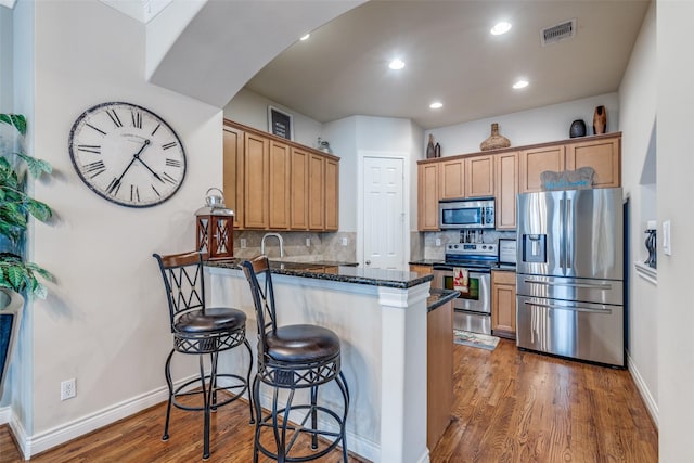 kitchen with a peninsula, tasteful backsplash, visible vents, and stainless steel appliances