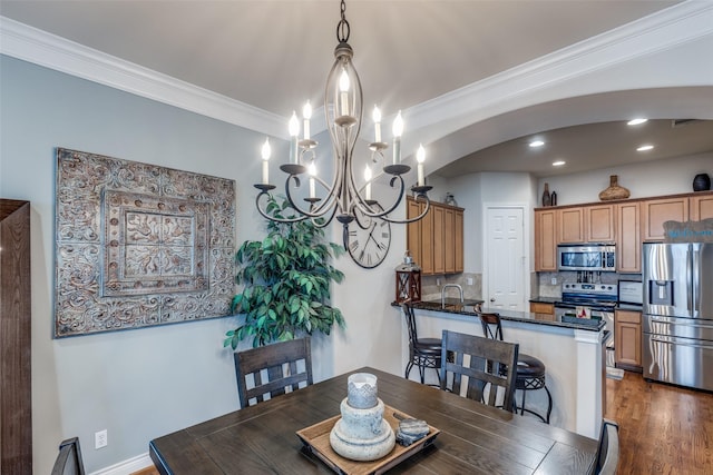 dining space featuring dark wood-style floors, recessed lighting, arched walkways, crown molding, and a chandelier