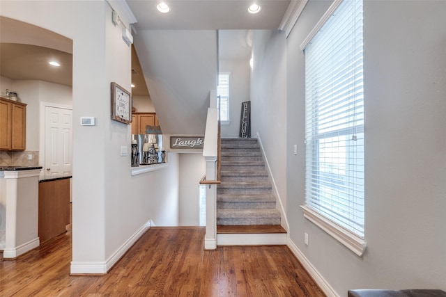 staircase with recessed lighting, wood finished floors, baseboards, and arched walkways