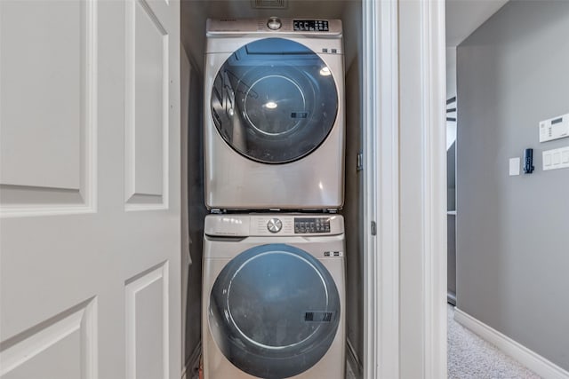 washroom featuring laundry area, stacked washer and clothes dryer, and baseboards