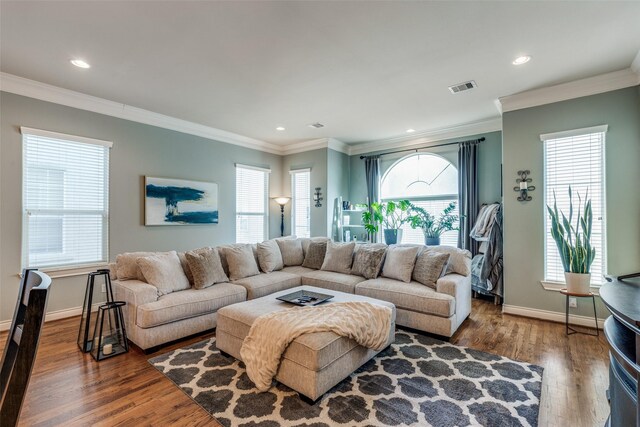 living area featuring visible vents, crown molding, baseboards, and wood finished floors