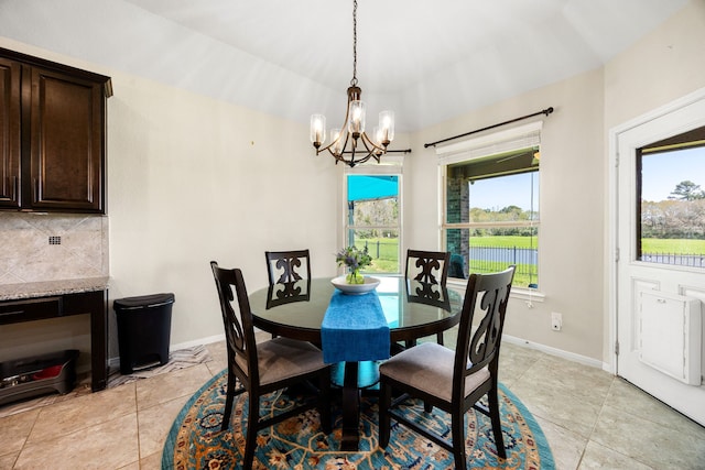 dining space featuring a notable chandelier, a healthy amount of sunlight, and baseboards