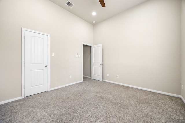 carpeted spare room featuring visible vents, a ceiling fan, recessed lighting, baseboards, and a towering ceiling