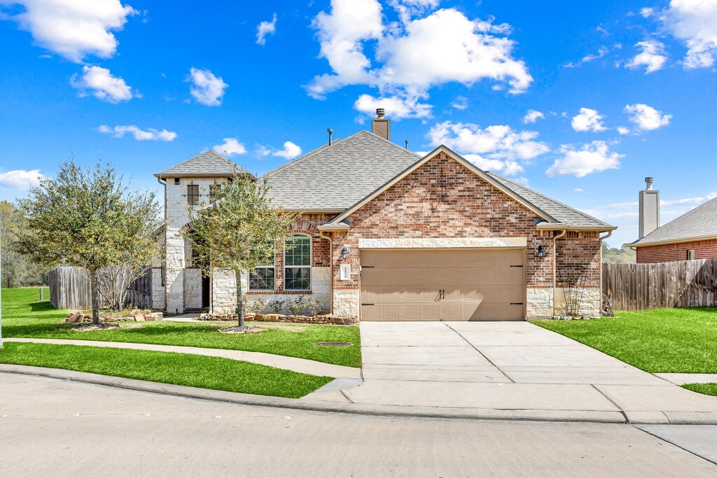 22958 Dale River Rd, Tomball, TX 77375 - french country inspired facade featuring fence, an attached garage, a front lawn, concrete driveway, and brick siding