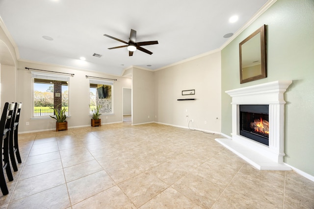 unfurnished living room featuring a glass covered fireplace, light tile patterned flooring, crown molding, baseboards, and ceiling fan