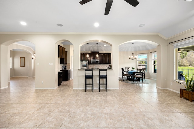 kitchen with tasteful backsplash, dark brown cabinets, ceiling fan, appliances with stainless steel finishes, and a kitchen breakfast bar