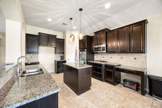 kitchen with visible vents, a kitchen island, a sink, decorative backsplash, and appliances with stainless steel finishes