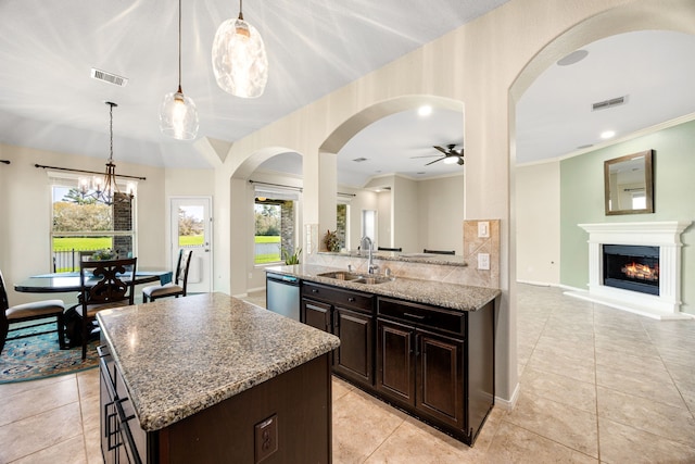 kitchen featuring visible vents, a kitchen island, dishwasher, ceiling fan with notable chandelier, and a sink