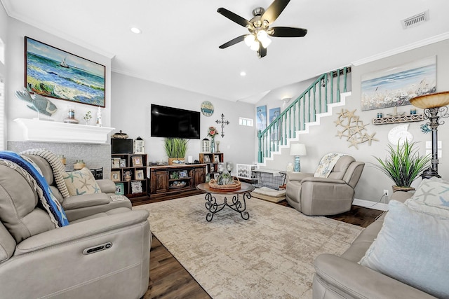 living room with visible vents, dark wood finished floors, stairway, crown molding, and ceiling fan