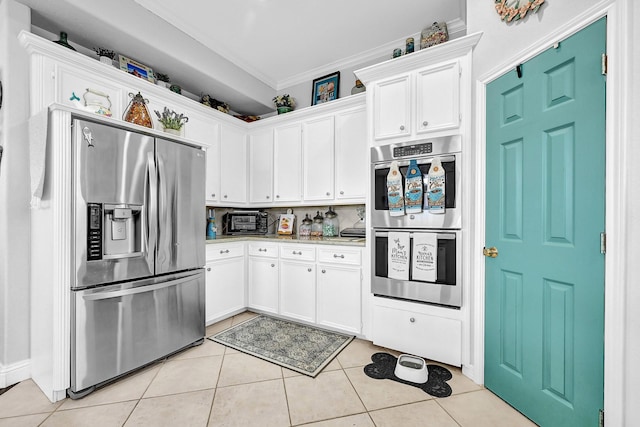 kitchen featuring ornamental molding, white cabinetry, appliances with stainless steel finishes, light tile patterned flooring, and light countertops