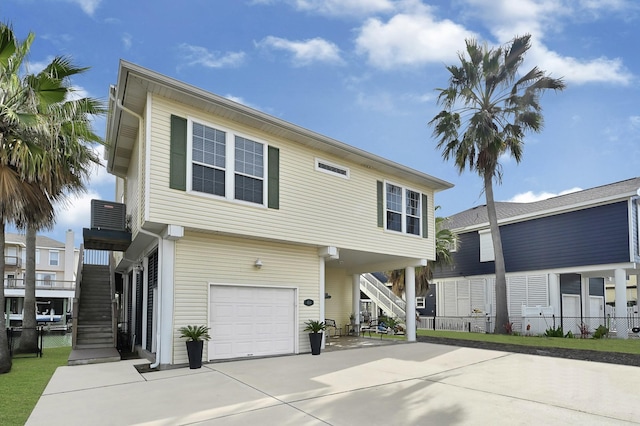 view of front of home featuring stairway, an attached garage, concrete driveway, and fence