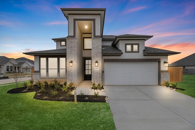 prairie-style house with a shingled roof, concrete driveway, a yard, and stucco siding