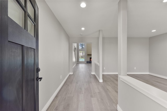 hallway featuring recessed lighting, light wood-style floors, and baseboards