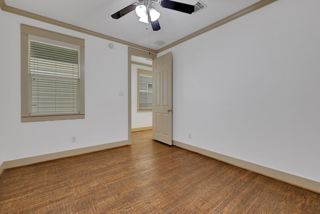 empty room featuring visible vents, ornamental molding, a ceiling fan, wood finished floors, and baseboards