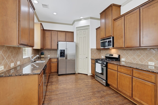 kitchen with visible vents, dark stone countertops, stainless steel appliances, and a sink