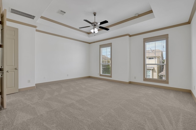 unfurnished room with a tray ceiling, plenty of natural light, light colored carpet, and visible vents