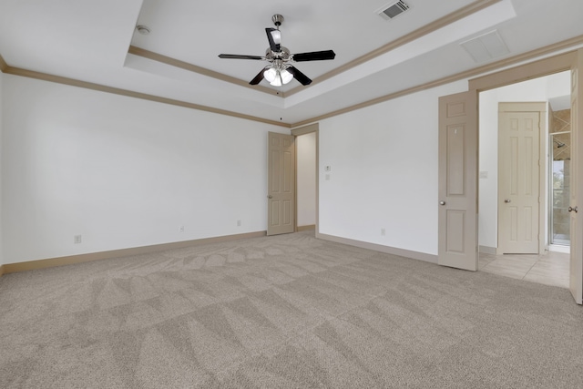 spare room with visible vents, crown molding, light colored carpet, a raised ceiling, and a ceiling fan