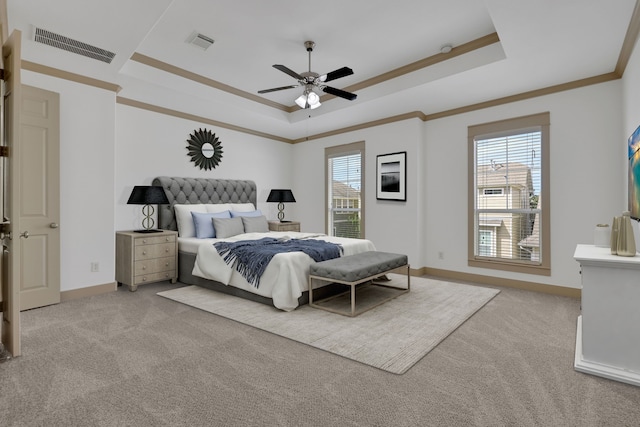 bedroom with a tray ceiling, multiple windows, light colored carpet, and visible vents