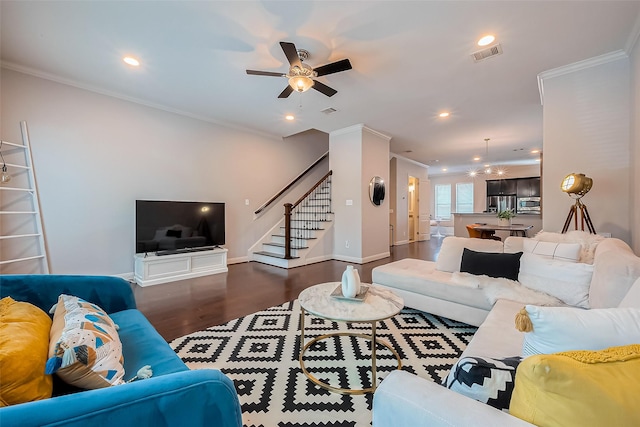 living area with stairway, a ceiling fan, visible vents, dark wood-type flooring, and crown molding