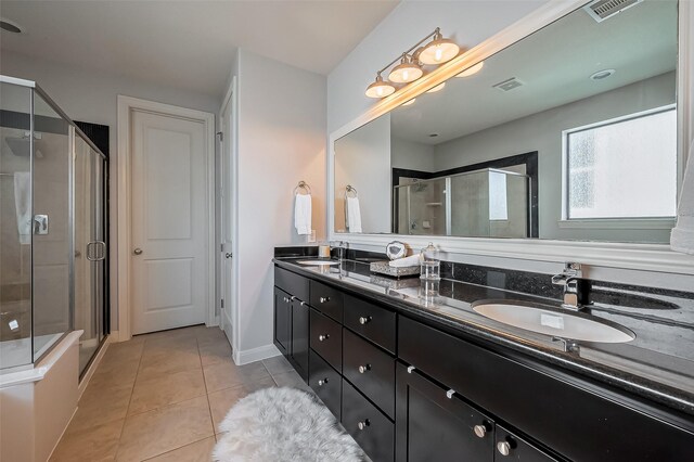 bathroom featuring tile patterned floors, a shower stall, double vanity, and a sink