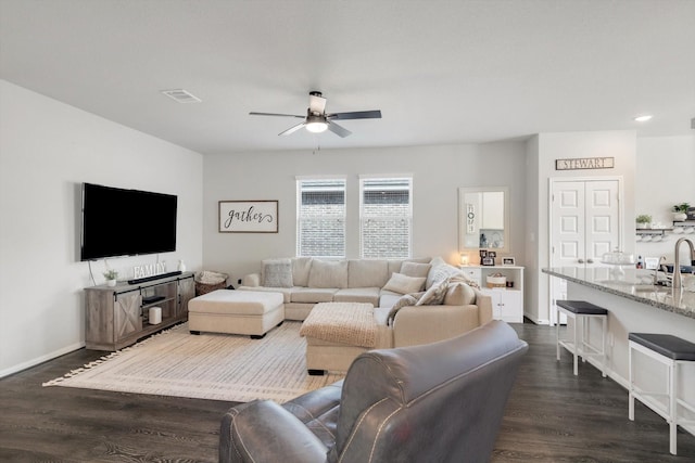 living room with baseboards, dark wood-style floors, visible vents, and ceiling fan