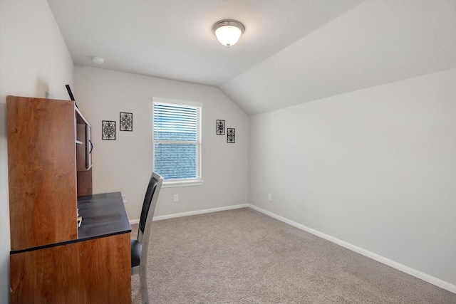 unfurnished office featuring vaulted ceiling, carpet flooring, and baseboards