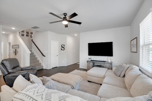 living room featuring stairs, dark wood-style floors, a ceiling fan, and visible vents