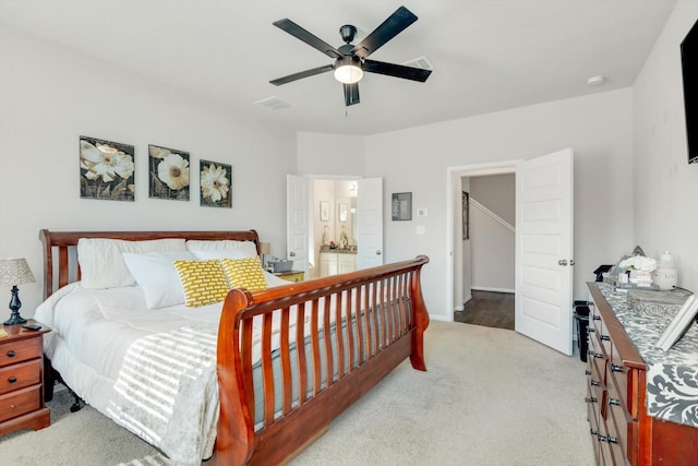 carpeted bedroom featuring visible vents, connected bathroom, and a ceiling fan