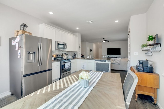 kitchen with tasteful backsplash, open floor plan, stainless steel appliances, white cabinets, and ceiling fan