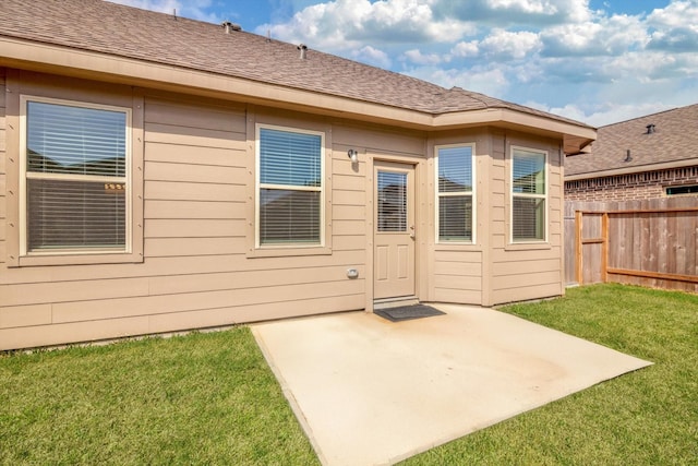 rear view of house featuring a patio area, fence, a lawn, and a shingled roof