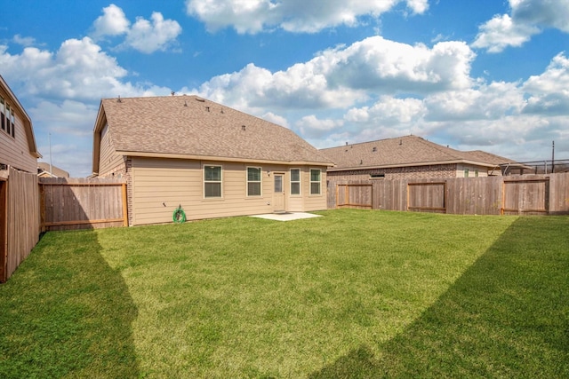 rear view of property featuring a yard, a patio, and a fenced backyard