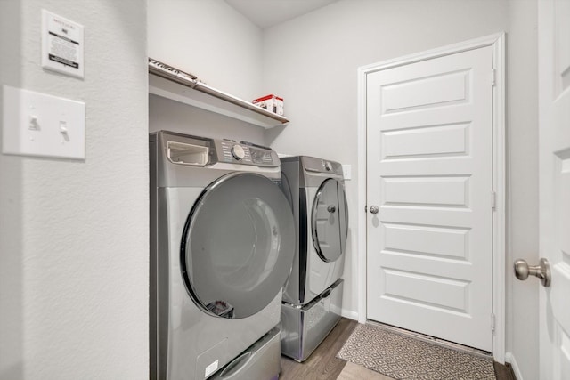 clothes washing area with laundry area, baseboards, dark wood-style flooring, and washer and clothes dryer