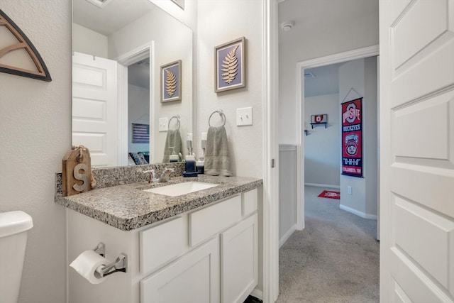 half bathroom with baseboards, toilet, and vanity