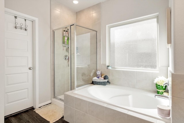 bathroom with a bath, a stall shower, and wood finished floors