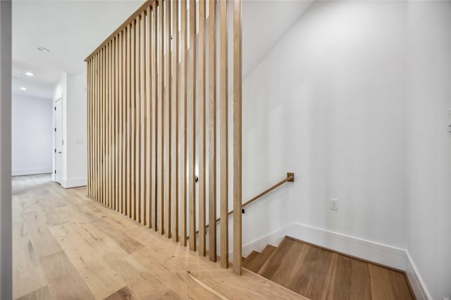 hallway with an upstairs landing, wood finished floors, recessed lighting, and baseboards