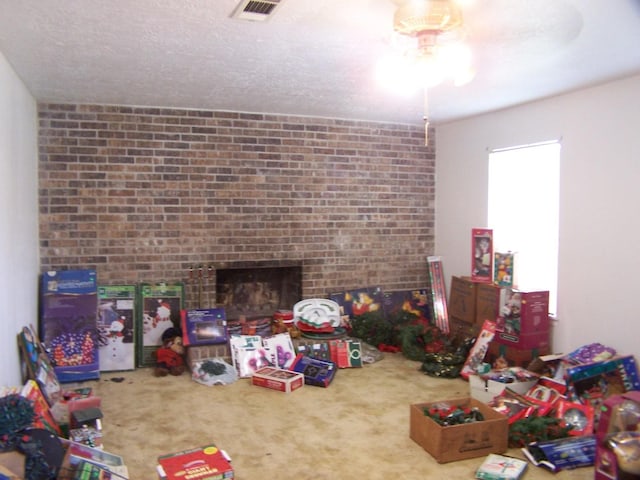 interior space featuring visible vents, a textured ceiling, a brick fireplace, and carpet