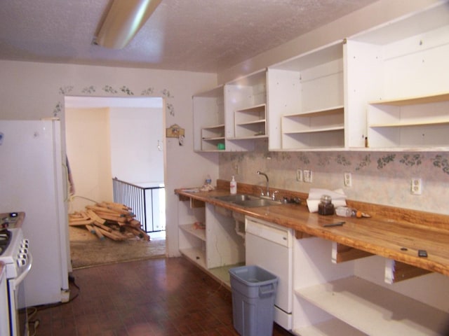 kitchen featuring white appliances, open shelves, brick floor, a sink, and white cabinets