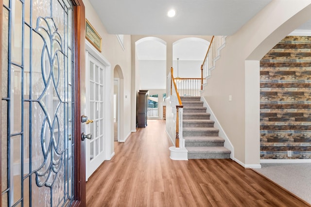 foyer entrance with stairway, wood finished floors, arched walkways, and baseboards